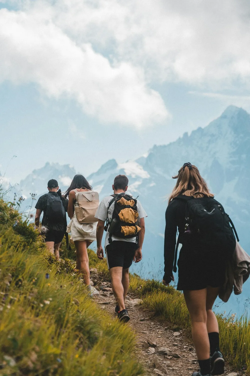 A group of trekkers with backpacks walking towards snow-capped mountains